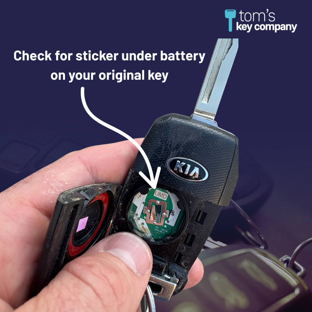 Close-up of a Kia car key fob with a sticker under the battery, against a dark background.